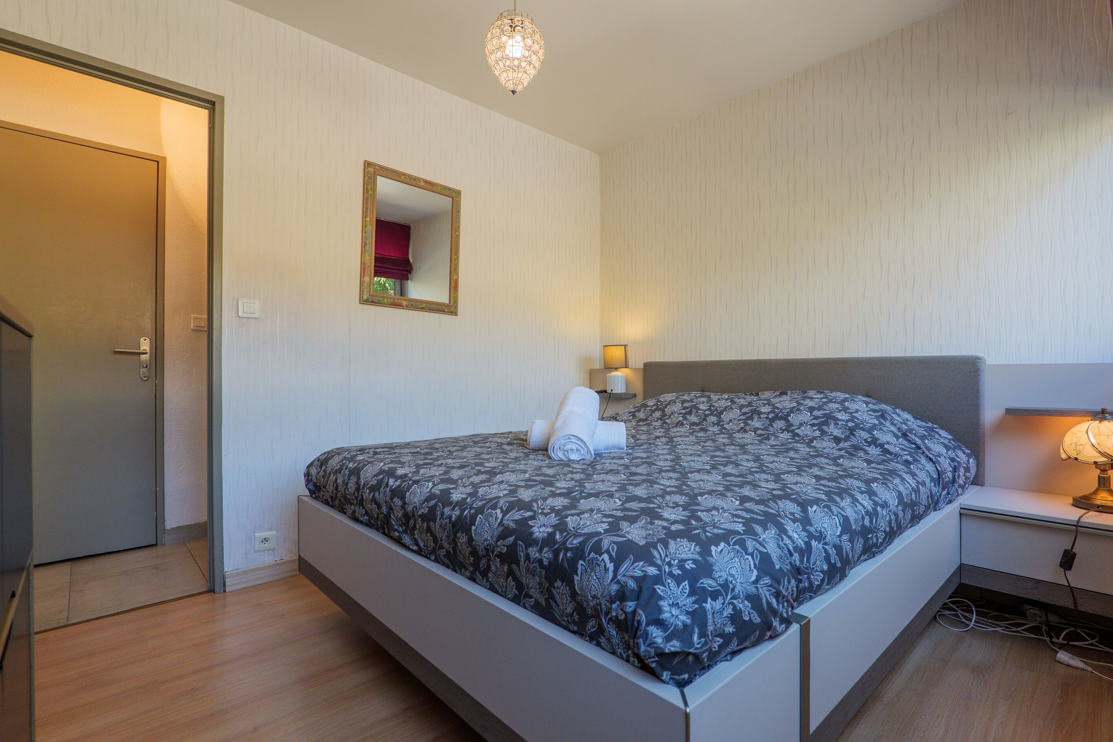Une chambre à coucher avec un lit, une table de chevet, une lampe et une porte.