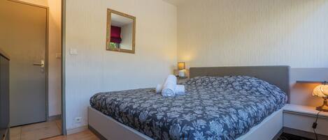 Une chambre à coucher avec un lit, une table de chevet, une lampe et une porte.