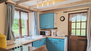 A kitchen with blue cabinets, a microwave, a coffee maker, and a sink. - Delightful 1-bedroom cottage in tranquil Sainte Price Melrand perfect getaway (Melrand)