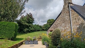 A stone building with a gravel path leading to a wooden door, surrounded by greenery and flowers. - Delightful 1-bedroom cottage in tranquil Sainte Price Melrand perfect getaway (Melrand)