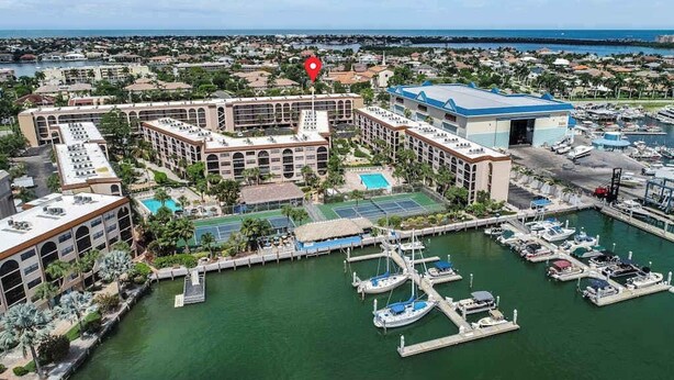 Un puerto deportivo con barcos amarrados, una piscina y un hotel con varias edificaciones.