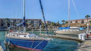 Un puerto deportivo con barcos amarrados, un edificio con ventanas arqueadas y un cielo despejado.