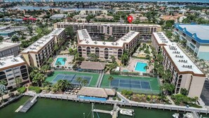 Un hotel con varias edificaciones, un puerto deportivo, canchas de tenis y una piscina.