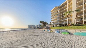 A beachfront hotel with multiple balconies, a pool area, and palm trees. - Spacious oceanfront condo with heated pool, pickleball, tennis, gym, & balcony (Marco Island)