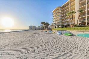 A beachfront hotel with multiple balconies, a pool area, and palm trees. - Spacious oceanfront condo with heated pool, pickleball, tennis, gym, & balcony (Marco Island)