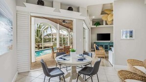 Comedor con mesa redonda, sillas y vista a una piscina exterior.