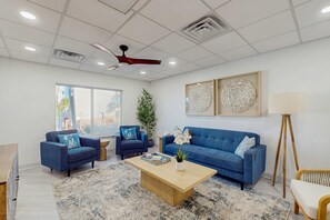 Un salon moderne avec un canapé bleu, deux fauteuils, une table basse en bois et un lampadaire.