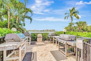 Une terrasse extérieure équipée de barbecues, d’une poubelle et d’un panneau indiquant qu’il faut nettoyer les barbecues après utilisation.