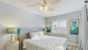A bedroom with a bed, a ceiling fan, a window with blinds, and two wall-mounted lamps. - Coastal condo with shared pool, tennis court, and washer & dryer (Fort Myers Beach)