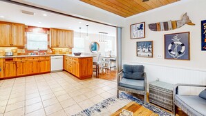 Eine Küche mit Holzausstattung, ein Essbereich mit Tisch und Stühlen sowie ein Wohnbereich mit Sofa und kleinem Tisch.