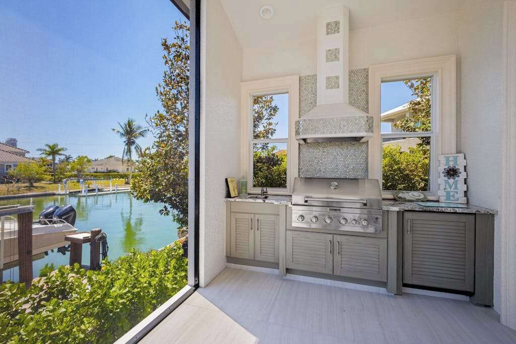 A modern kitchen with a large window overlooking a pool, built-in cabinets, and a stainless steel range.
