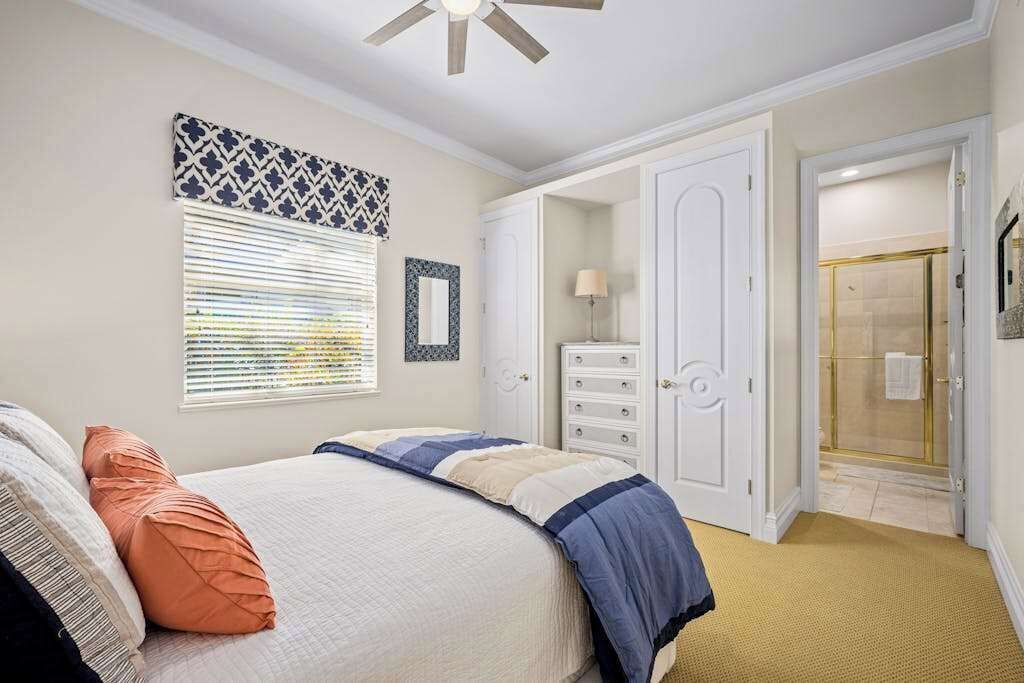Une chambre à coucher comprenant un lit, une armoire, un miroir et une porte donnant sur une salle de bain.