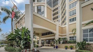 A multi-story hotel with a central atrium, large windows, and a flagpole. - Gulf-front condo with pool, hot tub, & central AC - snowbird-friendly (Marco Island)