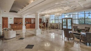 Eine großzügige Lobby mit hoher Decke, großen Fenstern und einem Chandelier.