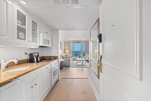 A modern kitchen with white cabinetry, a granite countertop, and a coffee maker.
