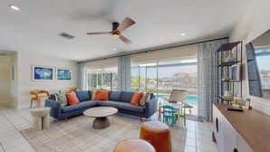 Ein modernes Wohnzimmer mit Ecksofa, rundem Couchtisch, Poufs und Deckenventilator.