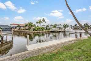 A marina with docks, a grassy area, and palm trees.