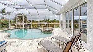 Una piscina cubierta al aire libre con sillas de descanso, un jacuzzi y vistas del paisaje circundante.