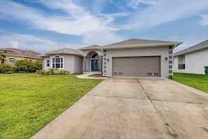 A residential house with a driveway, garage, and a well-maintained lawn. - Spacious home with private pool, spa, patio, grill, AC, & W/D (Port Charlotte)