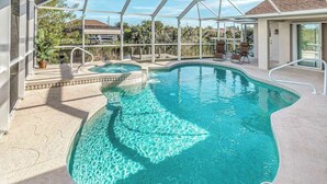 An indoor swimming pool with clear water, a sunshade structure, and a poolside area with chairs. - Dog-friendly home with private heated pool, grill, A/C, & washer/dryer (Port Charlotte)