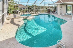 An indoor swimming pool with clear water, a sunshade structure, and a poolside area with chairs. - Dog-friendly home with private heated pool, grill, A/C, & washer/dryer (Port Charlotte)