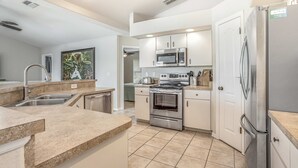 A modern kitchen with stainless steel appliances, a built-in oven, and a microwave. - Dog-friendly home with private heated pool, grill, A/C, & washer/dryer (Port Charlotte)