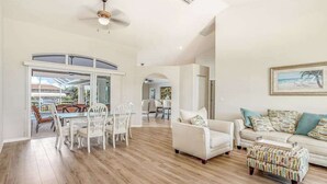 A spacious living area with a dining set, a sofa, and a patterned ottoman. - Dog-friendly home with private heated pool, grill, A/C, & washer/dryer (Port Charlotte)
