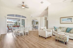 A spacious living area with a dining set, a sofa, and a patterned ottoman. - Dog-friendly home with private heated pool, grill, A/C, & washer/dryer (Port Charlotte)