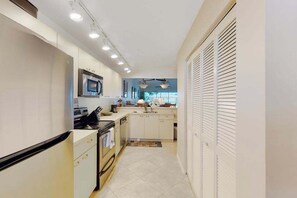 A narrow kitchen with white cabinetry, a microwave, and a stove. - Snowbird-friendly condo with pool access, lake views, W/D, and central AC (Naples)