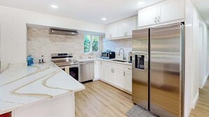 A modern kitchen with white cabinets, stainless steel appliances, and a large island. - Charming coastal getaway with lanai, bikes - near incredible beaches & golf (Naples)