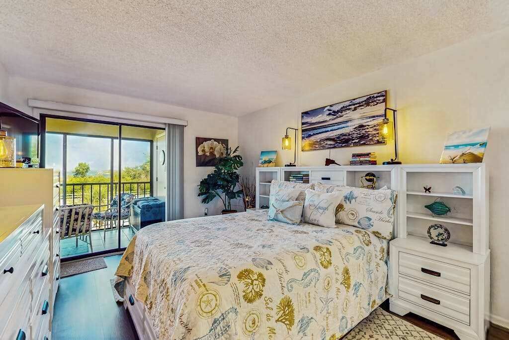 Une chambre à coucher avec un lit, un balcon, un bureau et une table de chevet.