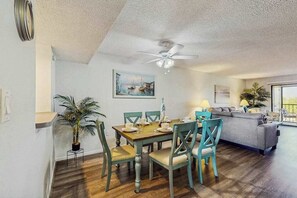 A dining area with a wooden table and chairs, a ceiling fan, and a painting on the wall. - Top-floor, Dog-Friendly, Snowbird Retreat Private Beach Access & Gulf Access (Port Charlotte)