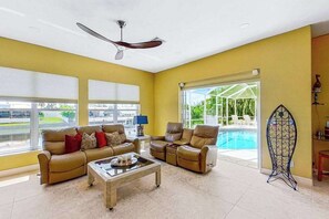 A spacious living room with a sofa set, a coffee table, and a ceiling fan. - Dog-friendly waterfront home with heated pool, lanai, central AC, & W/D (Matlacha Isles)