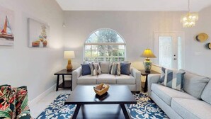 Una sala de estar con sofá, mesa de centro, lámpara y ventana.
