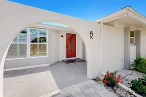A house with a red door, white exterior walls, and a covered porch area. - Bright Florida home with pool, gas grill, private pool, and washer/dryer (Rotonda West)