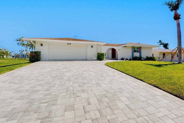 A single-story house with a garage, a paved driveway, and a well-maintained lawn. - Bright Florida home with pool, gas grill, private pool, and washer/dryer (Rotonda West)