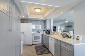 A modern kitchen with white cabinets, a built-in oven, a microwave, and a sink.
