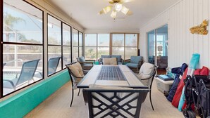 A room with a table, chairs, a ceiling fan, large windows, and luggage. - Palm-lined waterfront retreat with enclosed pool, inviting patio, & central AC (Rotonda West)