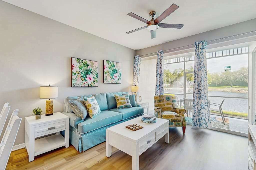 A living room with a blue sofa, white coffee table, and a ceiling fan.
