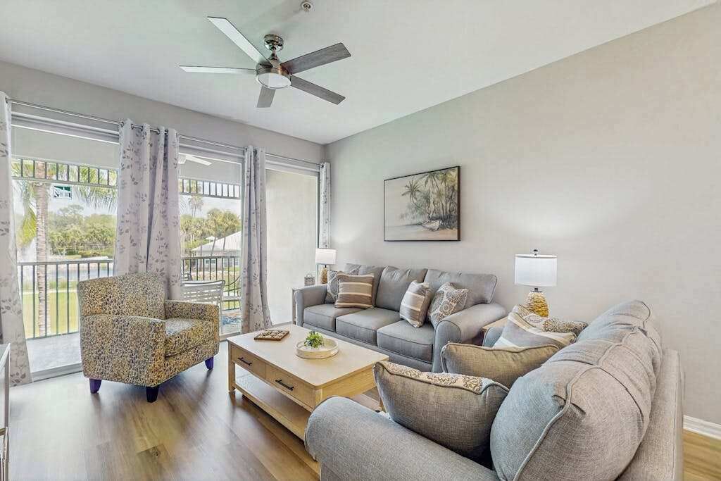 A living room with a sofa, armchair, coffee table, and a ceiling fan.
