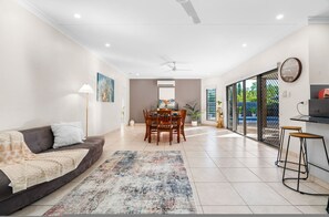 A modern living room with a sofa, coffee table, dining table, chairs, and a TV stand. - Zen Lotus Private Pool - Patio - Garage - Yard (Darwin)