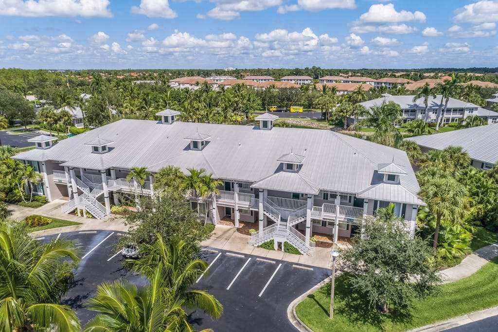 Et hotel med flere etager, et centralt atrium, parkering udendørs og grønne områder omkring.
