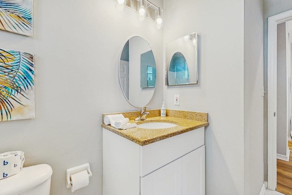 A bathroom with a white sink, a mirror, and a toilet.