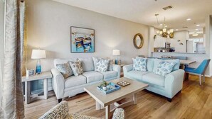 A modern living room with two sofas, a coffee table, and a dining area with a chandelier.