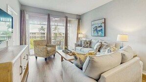 A living room with a sofa, armchairs, a coffee table, and a painting on the wall.