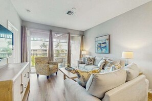 A living room with a sofa, armchairs, a coffee table, and a painting on the wall.