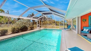 Una piscina con tetto in vetro, circondata da arredi da esterno e vista sul paesaggio.