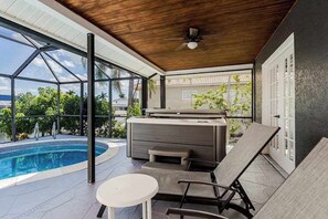 Ein Außenpoolbereich mit Whirlpool, Liegestühlen und Deckenventilator.