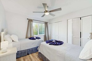 A bedroom with two beds, a ceiling fan, a window with curtains, and a white wardrobe. - Coastal Snowbird Retreat | 30+ Days (Port Charlotte)
