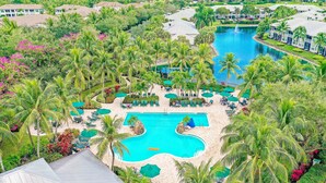 Un resort con piscina centrale, palme e un campo da golf.